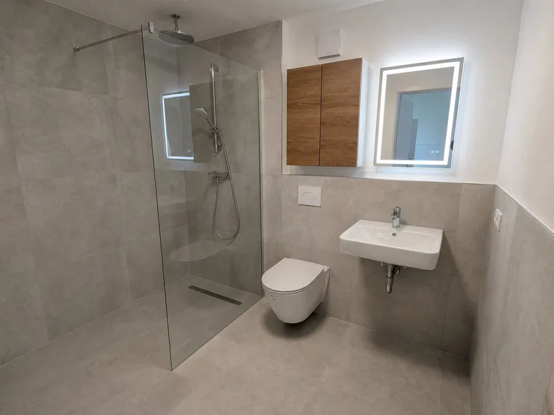 Duschbad mit bodengleicher Dusche, WC und beleuchtetem Spiegel