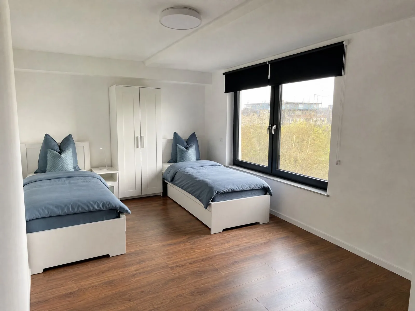 Zweibettzimmer mit zwei getrennten Einzelbetten, Kleiderschrank und Fenster