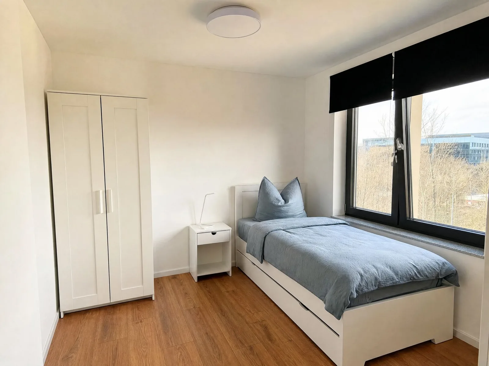Einzelzimmer mit weißem Kleiderschrank und Fenster
