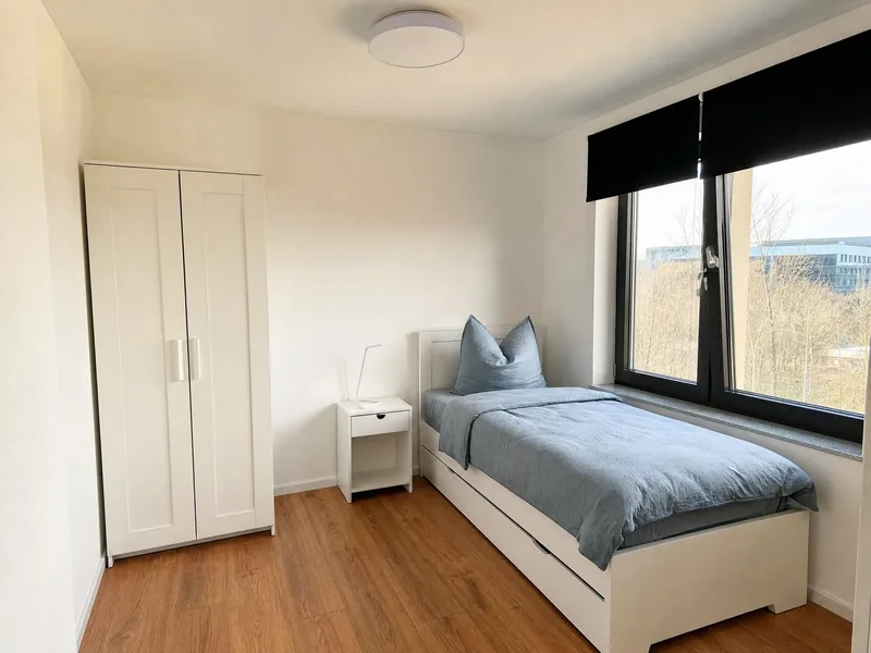 Einzelzimmer mit weißem Kleiderschrank und Fenster