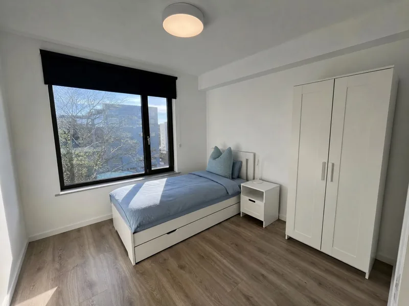 Einzelzimmer mit Bett, Nachttisch und Kleiderschrank