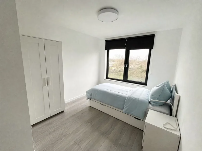 Einzelbett am Fenster mit Kleiderschrank daneben